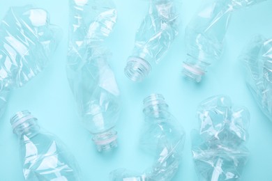 Photo of Crumpled plastic bottles on light blue background, flat lay