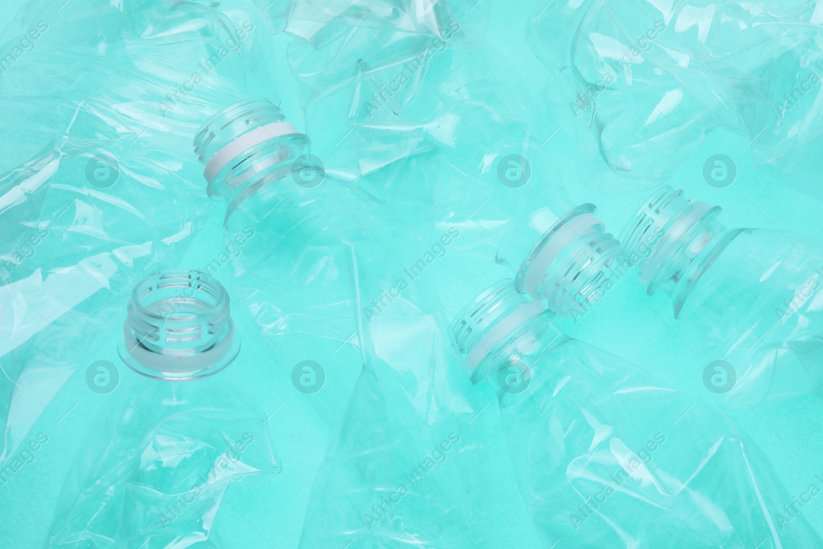 Photo of Crumpled plastic bottles on turquoise background, closeup