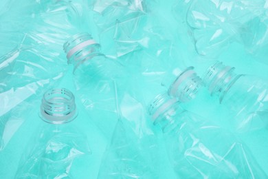 Photo of Crumpled plastic bottles on turquoise background, closeup