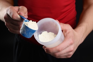 Sportsman adding protein into shaker on dark background, closeup