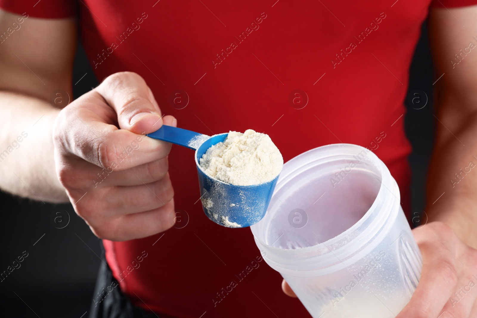 Photo of Sportsman adding protein into shaker on dark background, closeup