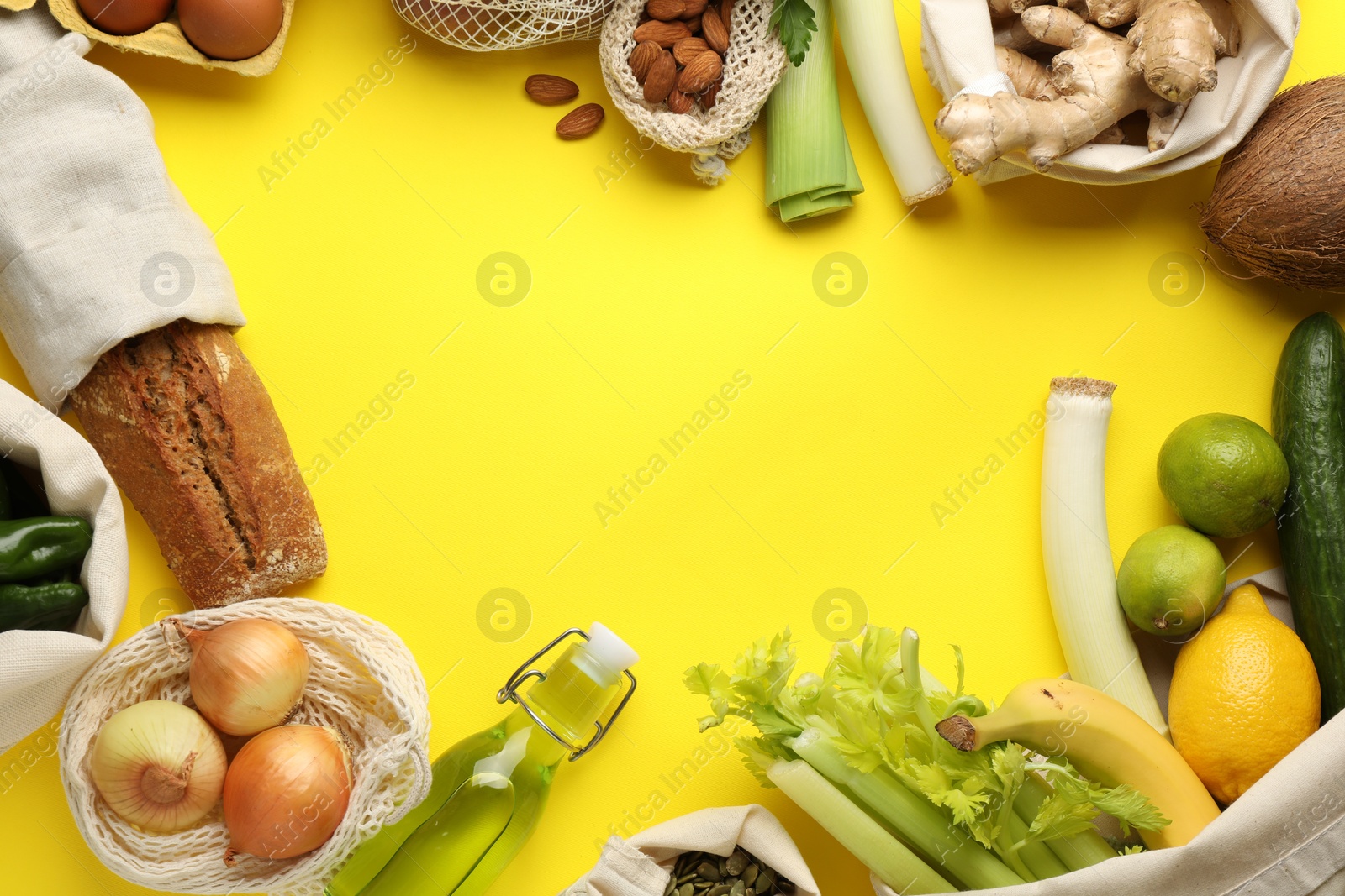 Photo of Frame of eco bags with different food products on yellow background, flat lay. Space for text