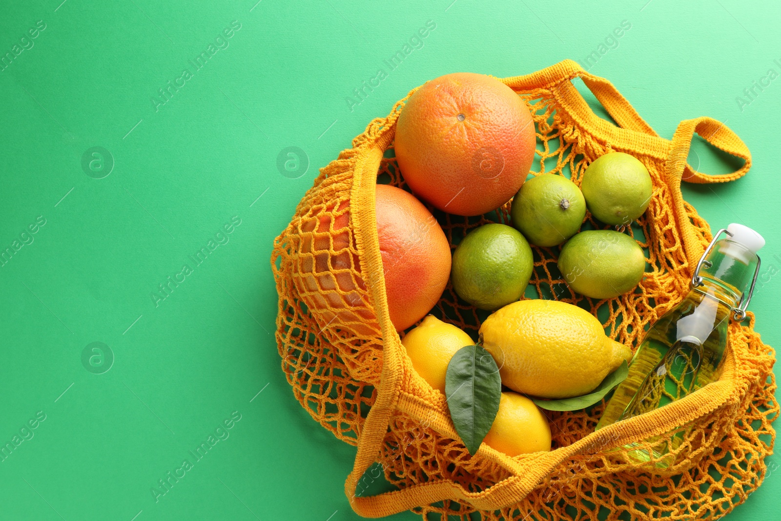 Photo of Eco bag with fruits and bottle of drink on green background, top view. Space for text