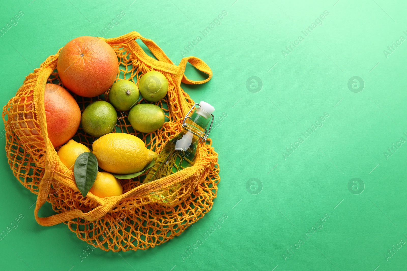 Photo of Eco bag with fruits and bottle of drink on green background, top view. Space for text