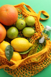 Photo of Eco bag with fruits and bottle of drink on green background, top view