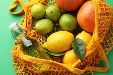 Photo of Eco bag with fruits and bottle of drink on green background, top view