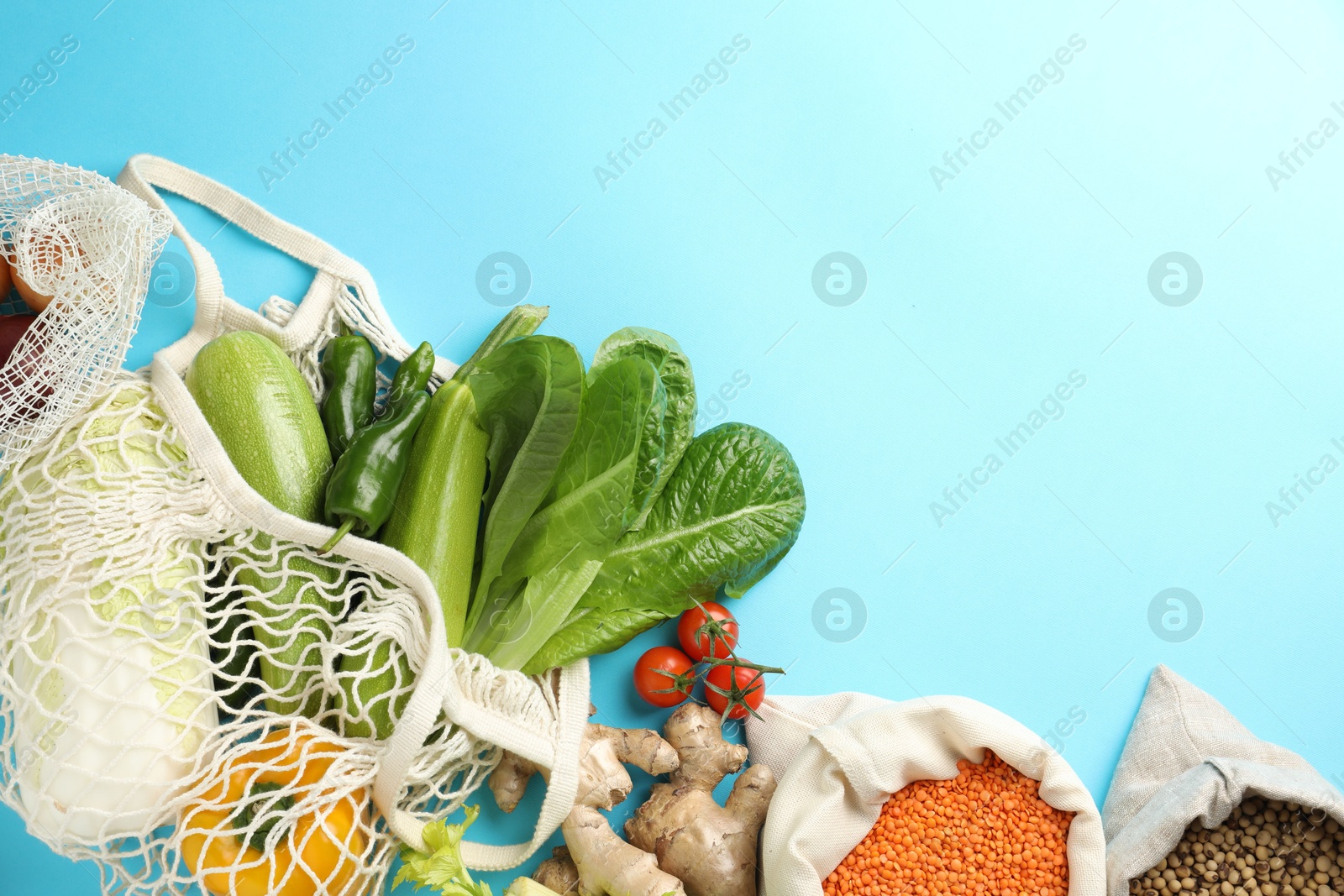 Photo of Shopper bags with products on light blue background, flat lay and space for text. Eco friendly lifestyle