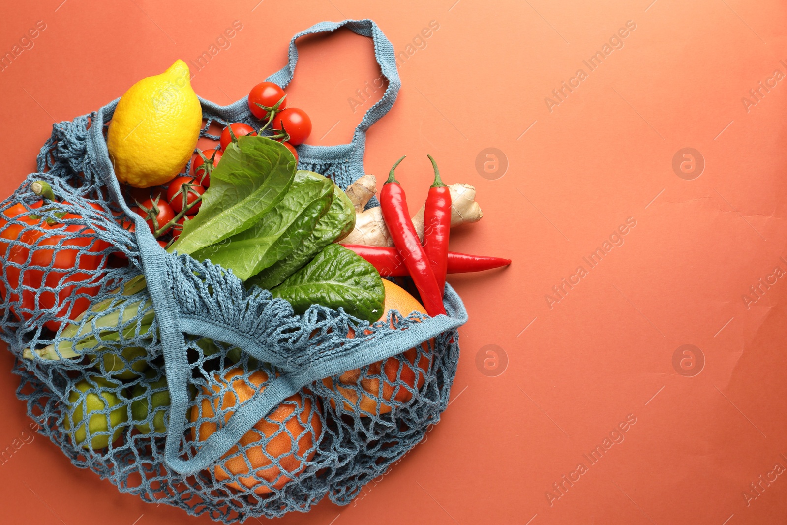 Photo of Net bag with products on orange background, top view and space for text. Eco friendly lifestyle