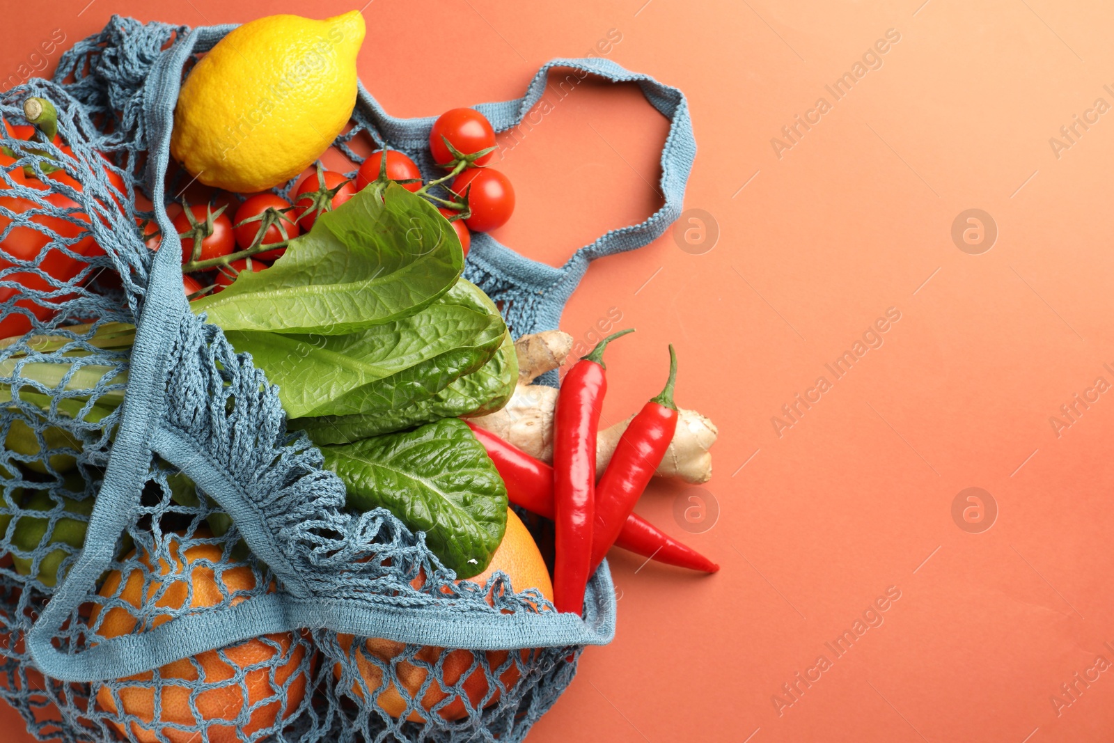 Photo of Net bag with products on orange background, top view and space for text. Eco friendly lifestyle