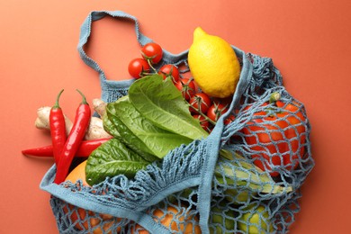 Photo of Net bag with products on orange background, top view. Eco friendly lifestyle