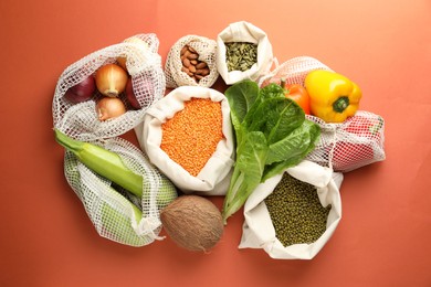 Photo of Shopper bags with products on orange background, flat lay. Eco friendly lifestyle