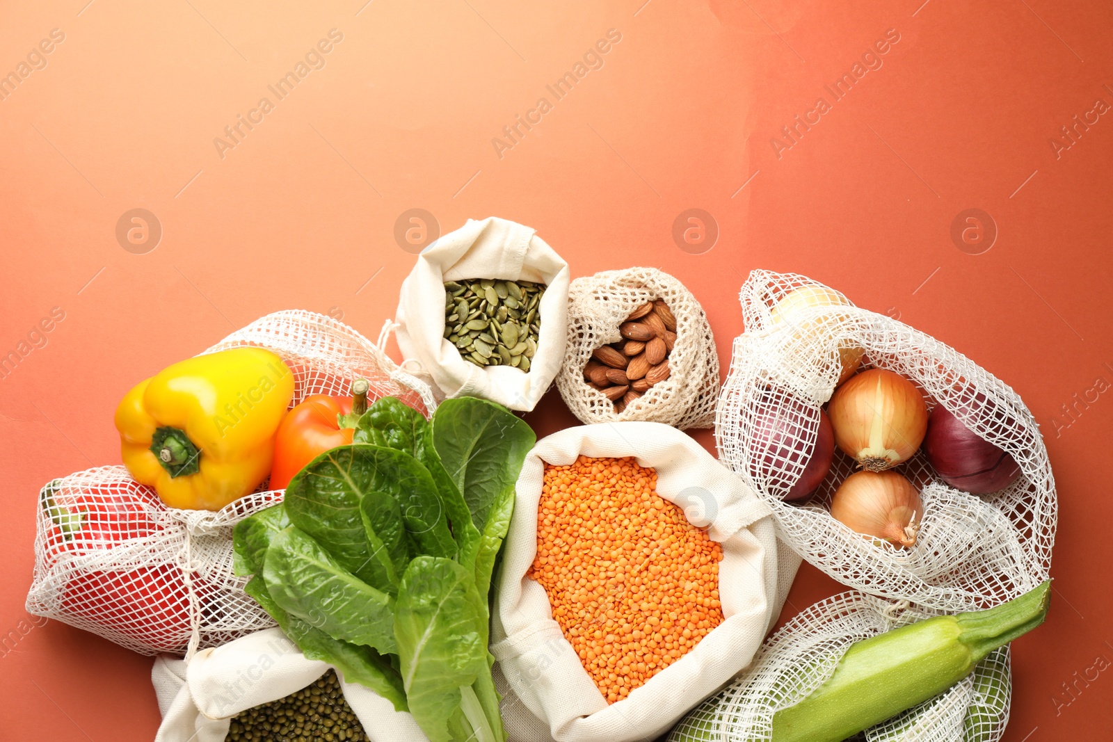 Photo of Shopper bags with products on orange background, flat lay. Eco friendly lifestyle