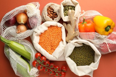 Photo of Shopper bags with products on orange background, flat lay. Eco friendly lifestyle