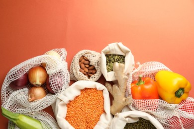 Photo of Shopper bags with products on orange background, flat lay and space for text. Eco friendly lifestyle