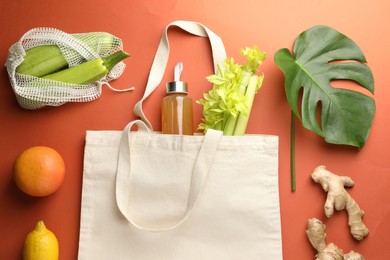 Photo of Shopper bag with products on orange background, flat lay. Eco friendly lifestyle