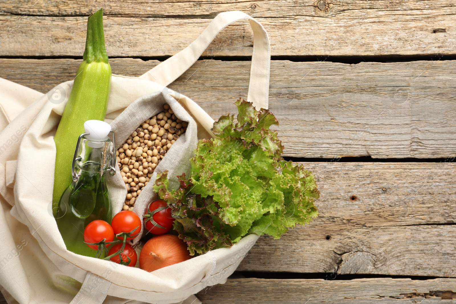 Photo of Shopper bag with products on wooden background, top view and space for text. Eco friendly lifestyle