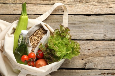 Photo of Shopper bag with products on wooden background, top view and space for text. Eco friendly lifestyle