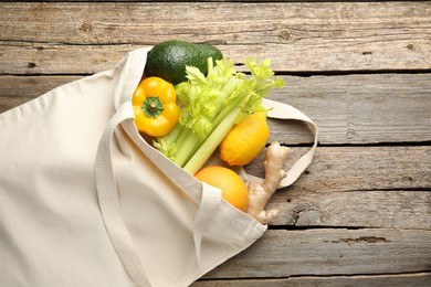 Photo of Shopper bag with products on wooden background, top view. Eco friendly lifestyle