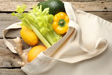 Photo of Shopper bag with products on wooden background, top view. Eco friendly lifestyle