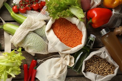 Photo of Shopper bags with products on wooden background, flat lay. Eco friendly lifestyle