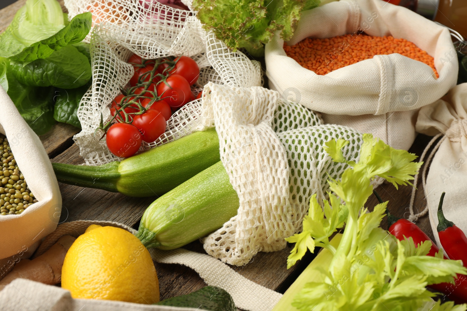 Photo of Shopper bags with products on wooden background, closeup. Eco friendly lifestyle