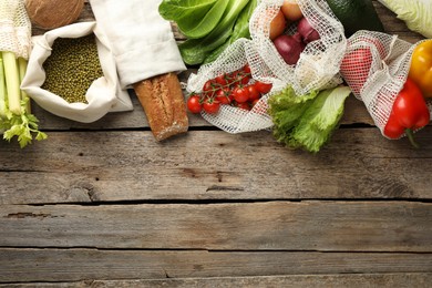 Photo of Shopper bags with products on wooden background, flat lay and space for text. Eco friendly lifestyle