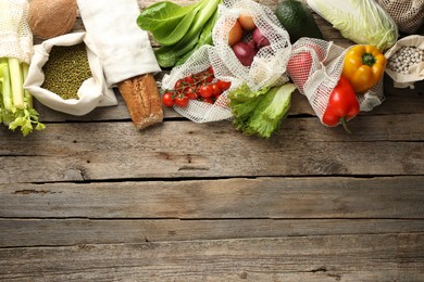 Photo of Shopper bags with products on wooden background, flat lay and space for text. Eco friendly lifestyle