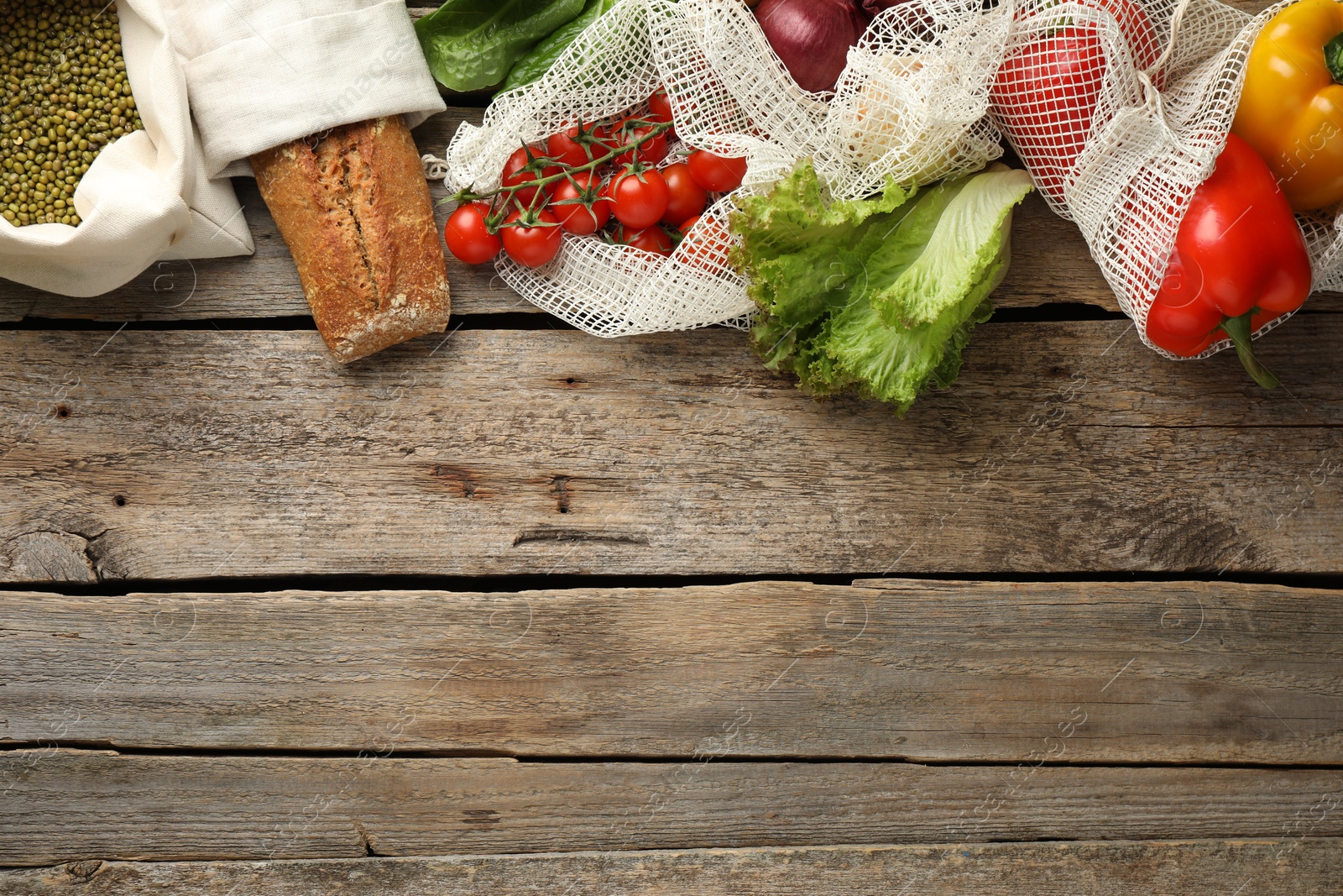 Photo of Shopper bags with products on wooden background, flat lay and space for text. Eco friendly lifestyle