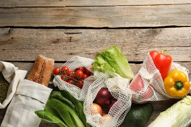 Photo of Shopper bags with products on wooden background, flat lay and space for text. Eco friendly lifestyle