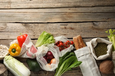 Photo of Shopper bags with products on wooden background, flat lay and space for text. Eco friendly lifestyle