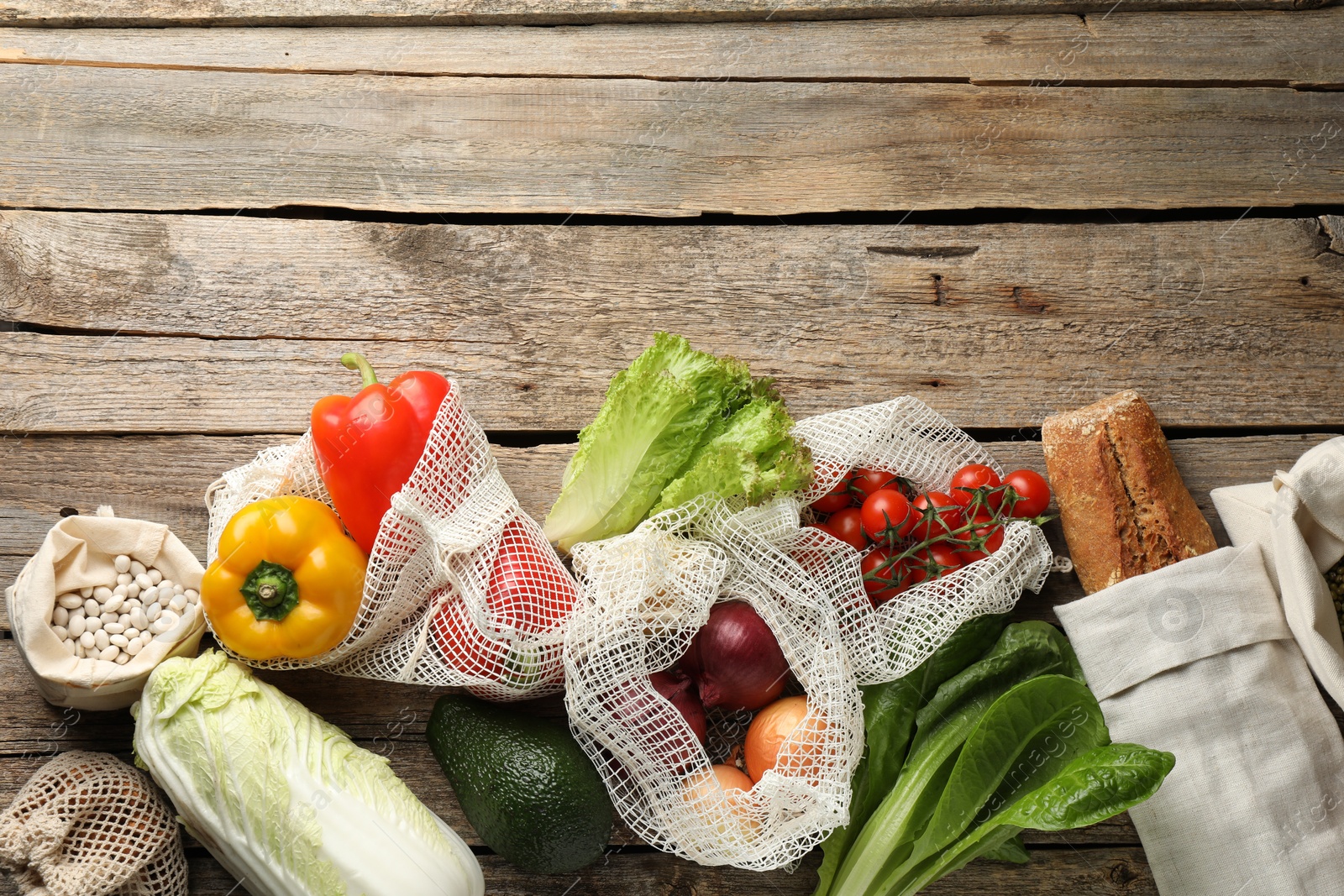 Photo of Shopper bags with products on wooden background, flat lay and space for text. Eco friendly lifestyle