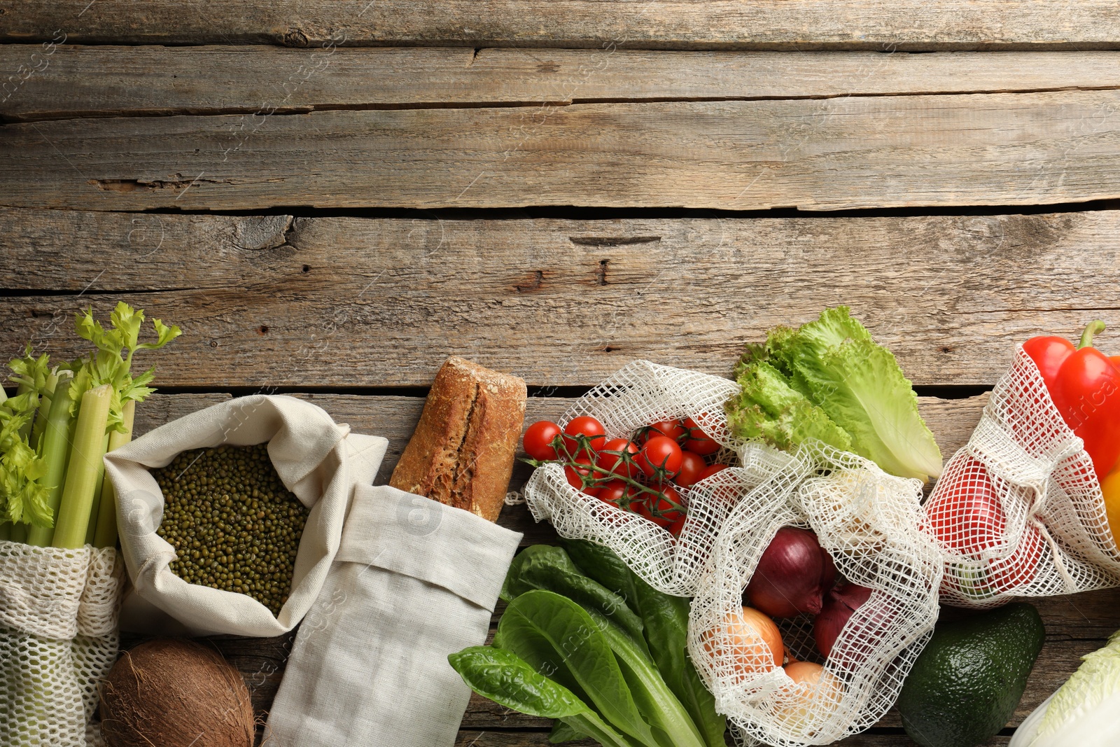 Photo of Shopper bags with products on wooden background, flat lay and space for text. Eco friendly lifestyle