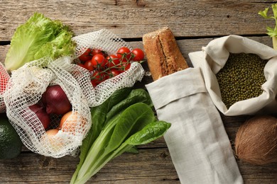 Photo of Shopper bags with products on wooden background, flat lay. Eco friendly lifestyle