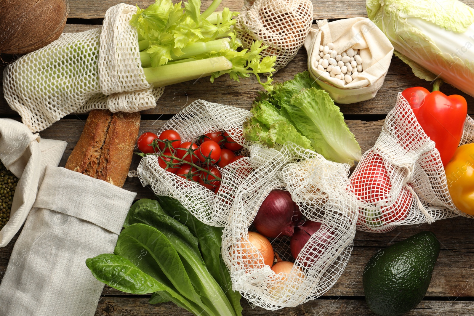 Photo of Shopper bags with products on wooden background, flat lay. Eco friendly lifestyle