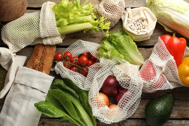 Photo of Shopper bags with products on wooden background, flat lay. Eco friendly lifestyle