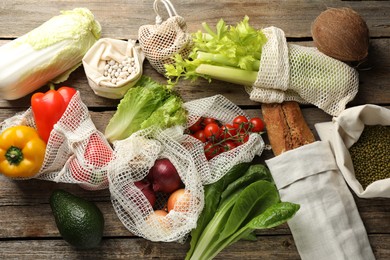 Photo of Shopper bags with products on wooden background, flat lay. Eco friendly lifestyle