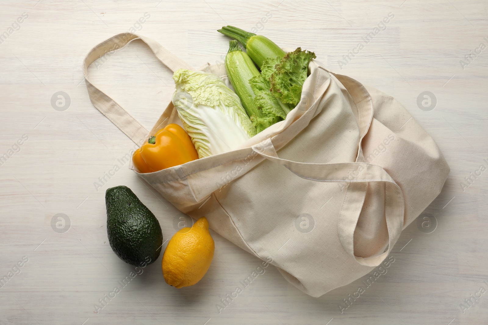 Photo of Shopper bag with products on white wooden background, top view. Eco friendly lifestyle