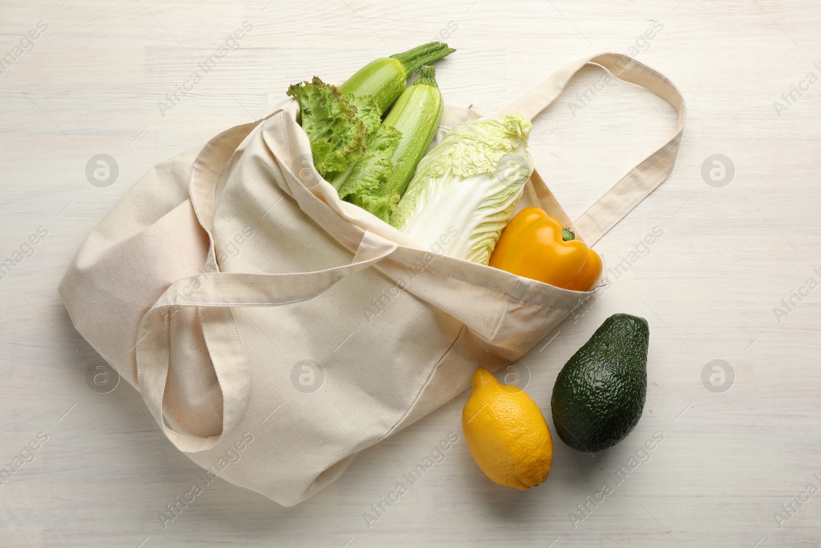 Photo of Shopper bag with products on white wooden background, top view. Eco friendly lifestyle