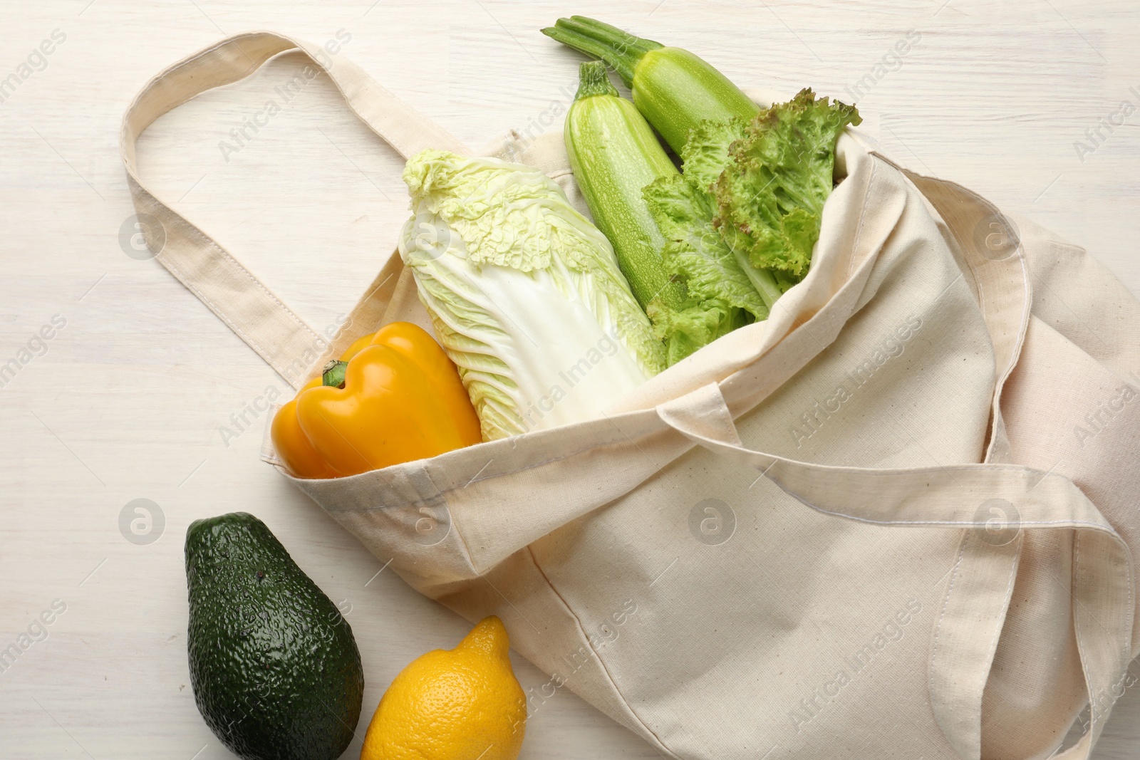 Photo of Shopper bag with products on white wooden background, top view. Eco friendly lifestyle