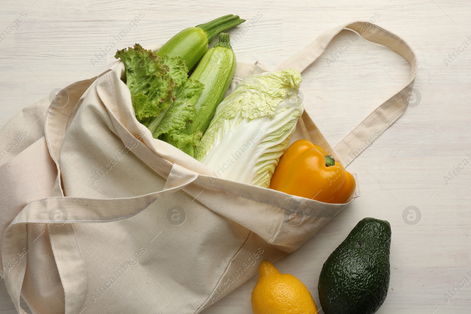 Photo of Shopper bag with products on white wooden background, top view. Eco friendly lifestyle