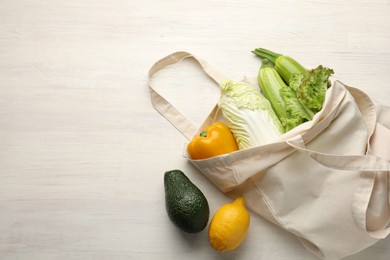 Photo of Shopper bag with products on white wooden background, top view and space for text. Eco friendly lifestyle