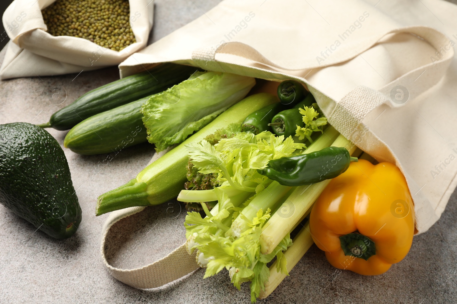 Photo of Shopper bag with products on grey background, closeup. Eco friendly lifestyle