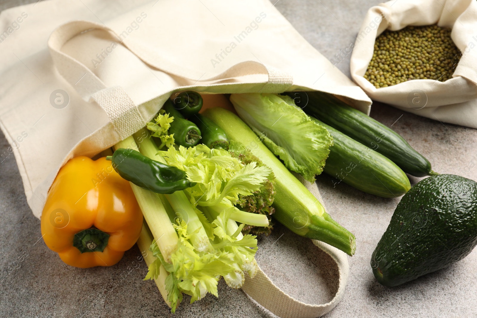 Photo of Shopper bag with products on grey background, closeup. Eco friendly lifestyle