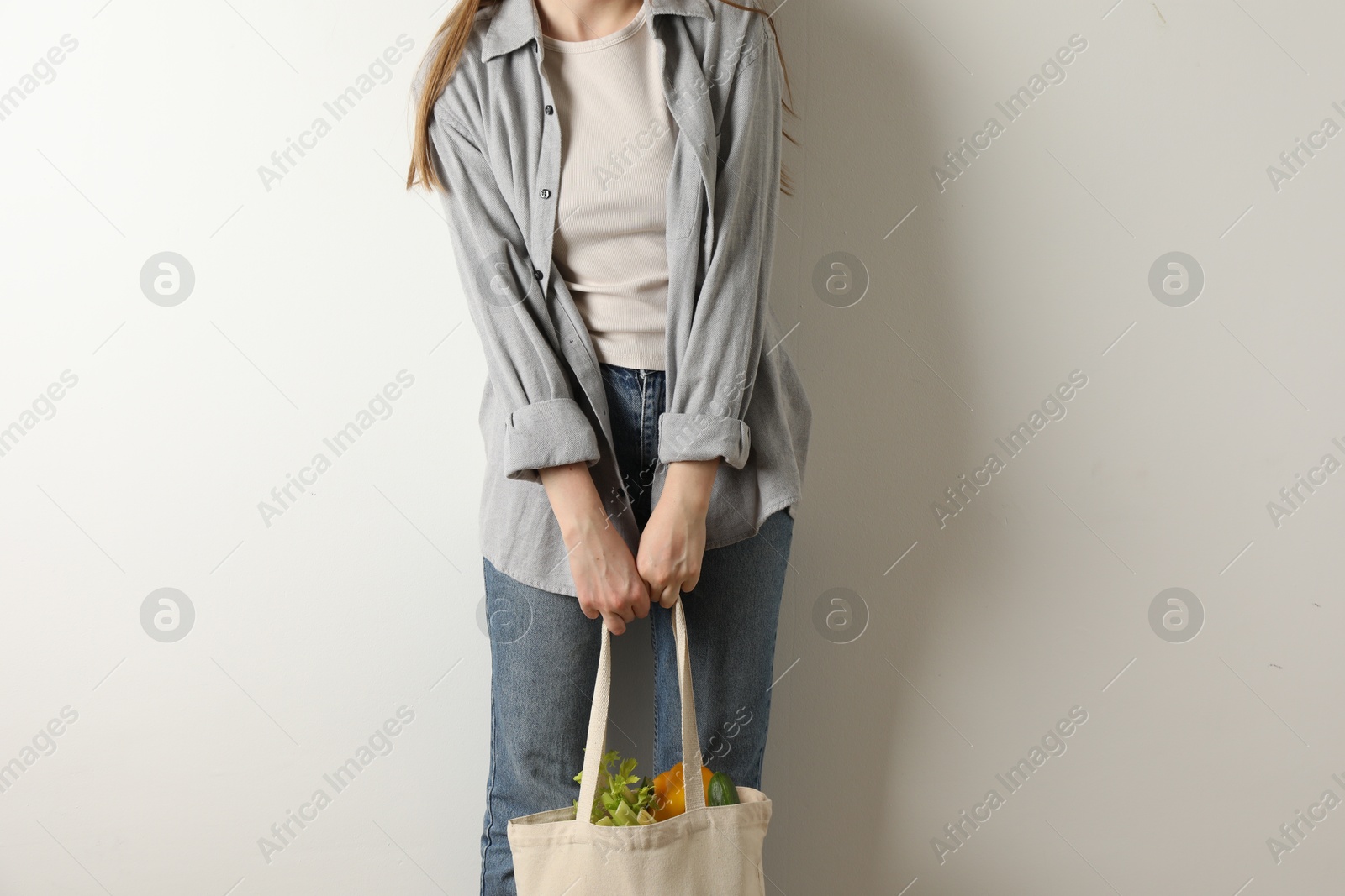 Photo of Woman holding shopper bag with groceries on white background, closeup. Eco friendly lifestyle