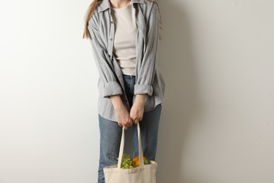 Photo of Woman holding shopper bag with groceries on white background, closeup. Eco friendly lifestyle