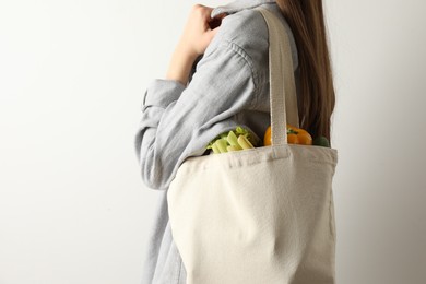 Photo of Woman holding shopper bag with groceries on white background, closeup and space for text. Eco friendly lifestyle