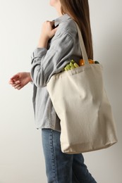 Photo of Woman holding shopper bag with groceries on white background, closeup. Eco friendly lifestyle