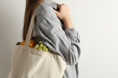 Photo of Woman holding shopper bag with groceries on white background, closeup. Eco friendly lifestyle