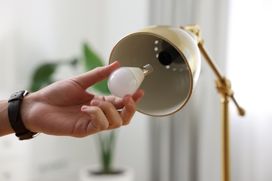 Photo of Man changing light bulb in lamp at home, closeup