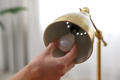 Photo of Man changing light bulb in lamp at home, closeup